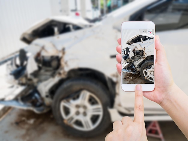 Femmina che utilizza lo smartphone mobile che scatta foto del danno da incidente d'auto per l'assicurazione