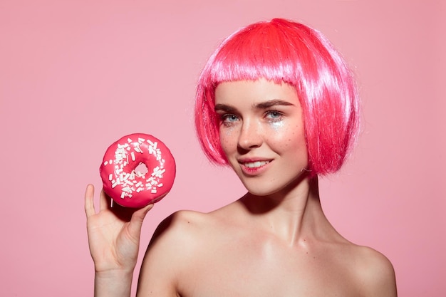 Femmina con capelli rosa che tiene ciambella