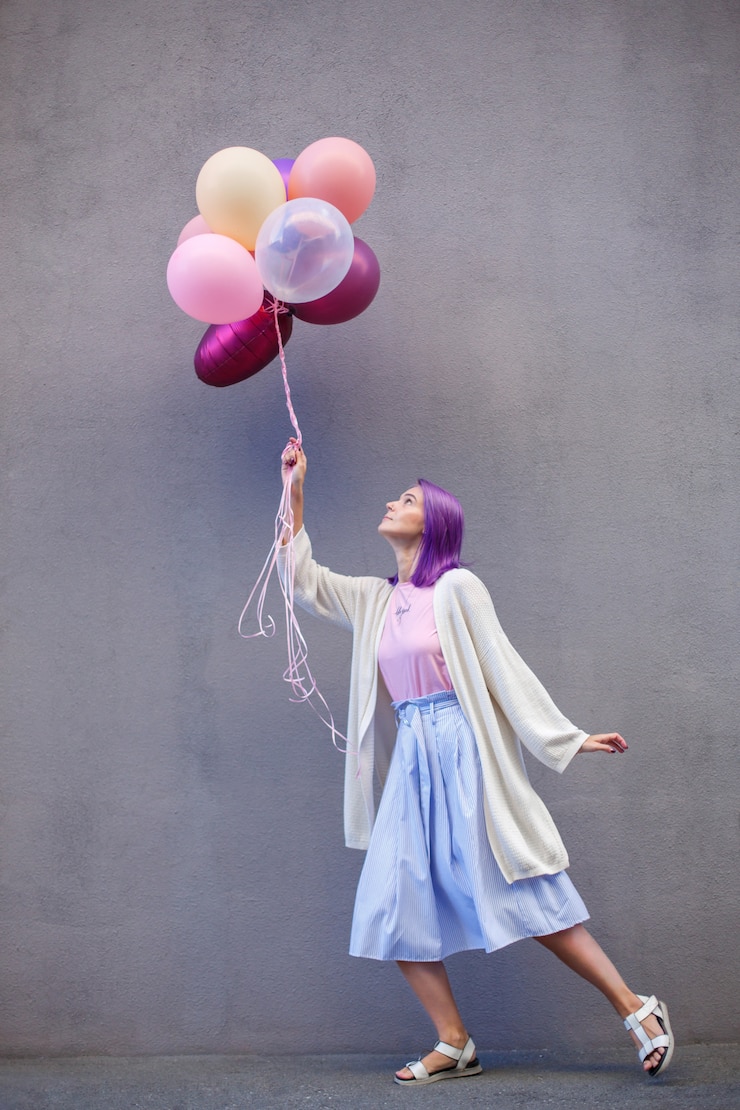 Foto femmina con capelli viola in piedi su una gamba sola con un mazzo di airballoons