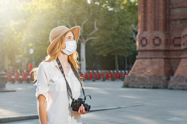 Femmina giovane fotografo professionista in viaggio e scattare foto indossando una maschera per il viso all'aperto.