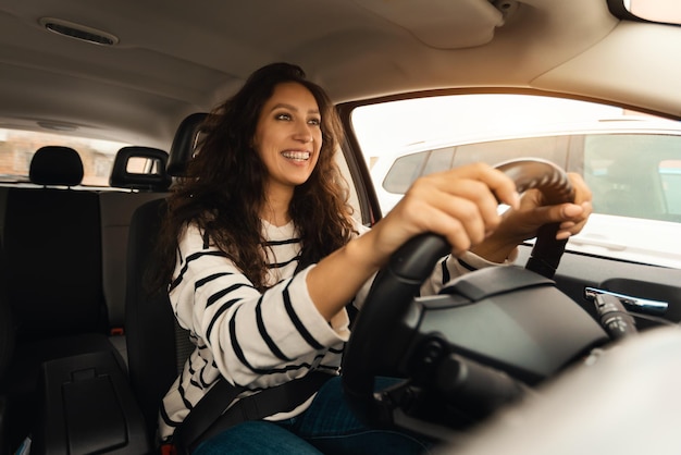 Femmina sorridente alla guida di una nuova auto in città