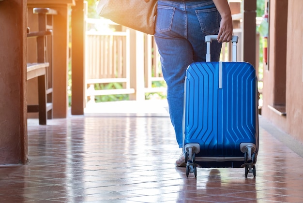 Femmina trascinando una valigia per lasciare la stanza in vacanza Vista posteriore del concetto di viaggio e stile di vita