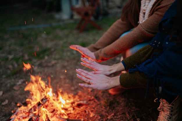 Femmine irriconoscibili che scaldano le mani nel calore del fuoco.