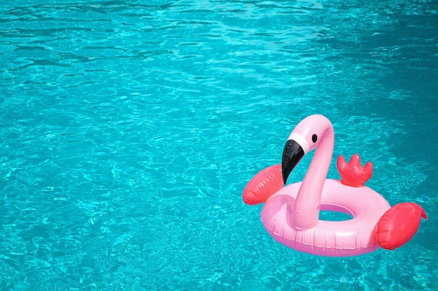 Fenicottero rosa gonfiabile nell&#39;acqua blu della piscina