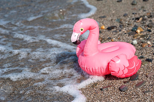 Fenicottero rosa gonfiabile per la piscina sulla spiaggia vicino all'acqua