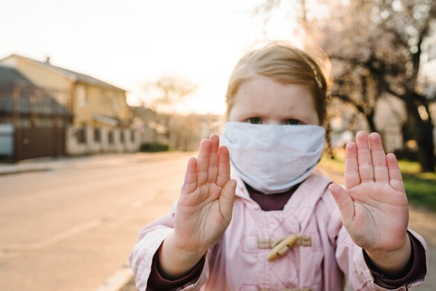 Fermare il coronavirus e le malattie epidemiche del virus. Bambino in buona salute nella mascherina protettiva medica che mostra l'arresto di gesto. Protezione della salute e prevenzione durante l'influenza e l'epidemia