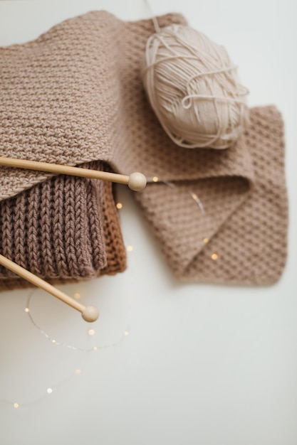 Ferri da maglia con fili di filato beige Concetto di hobby per le donne Accessori per maglieria