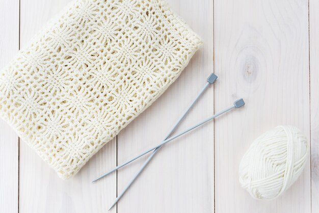 Ferri da maglia con una matassa di filo e un panno su un tavolo di legno