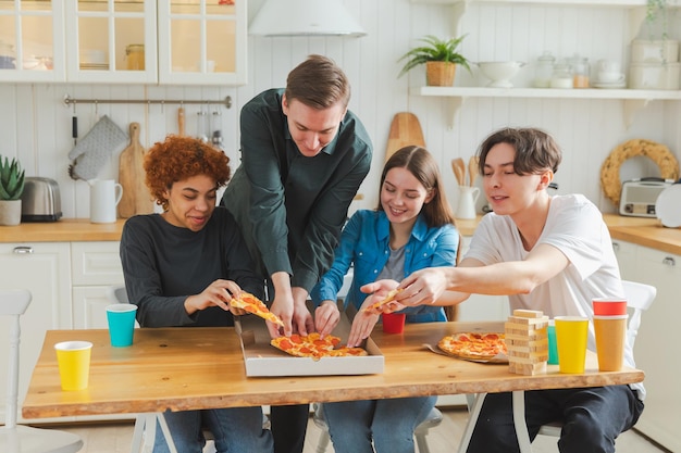 Festa a casa gioiosa diversi amici mangiano ordinato pizza per festa a casa gruppo felice razza mista