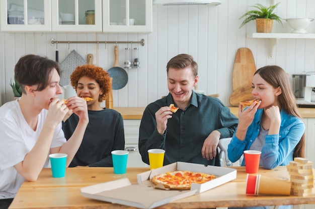 Festa a casa gioiosa diversi amici mangiano ordinato pizza per festa a casa gruppo felice razza mista