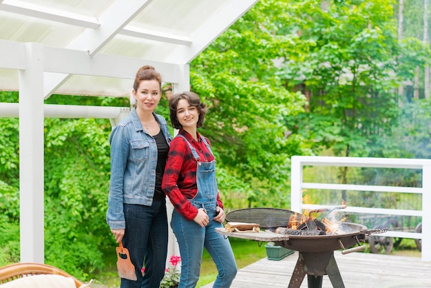 Festa barbecue in giardino con mamma e figlia alla griglia in campagna