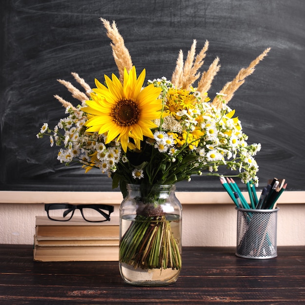 Festa degli insegnanti. Bordo di gesso nero e fiori di campo freschi in vaso