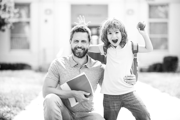 Festa degli insegnanti padre e figlio americani che camminano attraverso il parco della scuola famiglia felice nel cortile della scuola