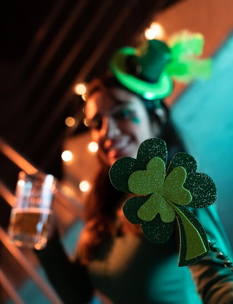 Festa del giorno di San Patrizio con una donna sullo sfondo che tiene in mano un trifoglio e un bicchiere di birra