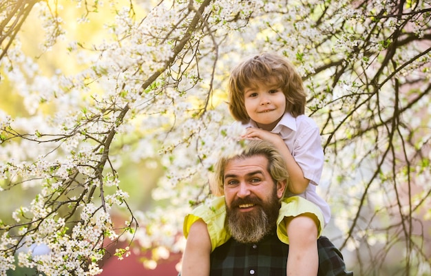 Festa del papà Bambino che si diverte con papà Famiglia felice Ragazzino e padre sullo sfondo della natura Primavera Hipster che trasporta sulle spalle il bambino Uomo brutale barbuto buon padre Papà e figlio Miglior papà di sempre