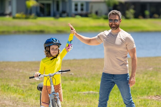 Festa del papà padre e figlio in sella a una bicicletta sulla strada alla festa del papà concetto di famiglia amichevole p