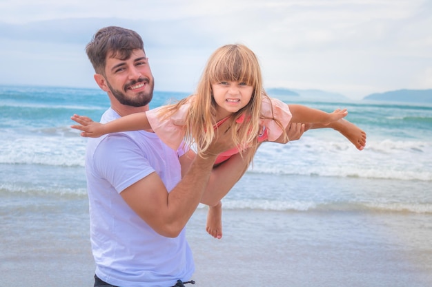 Festa del papà. Papà e figlia che giocano insieme all'aperto su una spiaggia estiva