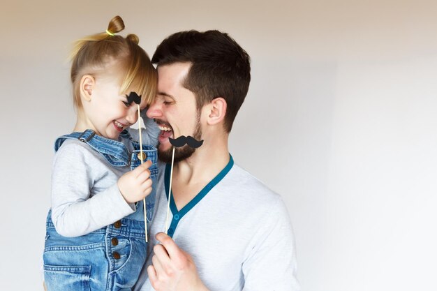 Festa del papà Una ragazza bionda che indossa una salopette di jeans abbraccia e ride con suo padre