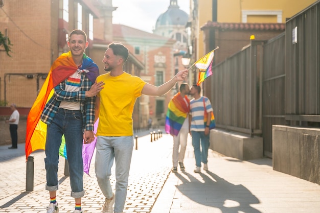 Festa dell'orgoglio gay nelle coppie maschili della città che camminano verso la dimostrazione con il concetto lgbt di bandiere arcobaleno
