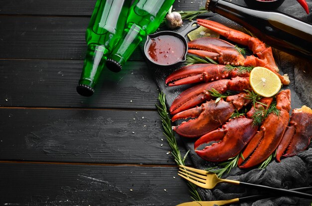 Festa della birra. Birra, snack e chele di aragosta su sfondo nero. Stile rustico. Prelibatezze di mare.