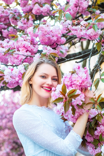 Festa della donna, 8 marzo. Bella donna con albero in fiore Sakura e giornata di sole.