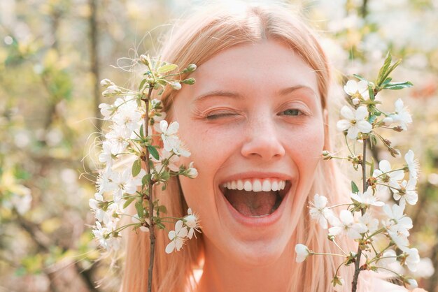 Festa della donna 8 marzo Ritratto divertente di donna bionda sul motivo a fiori primaverili Primo piano