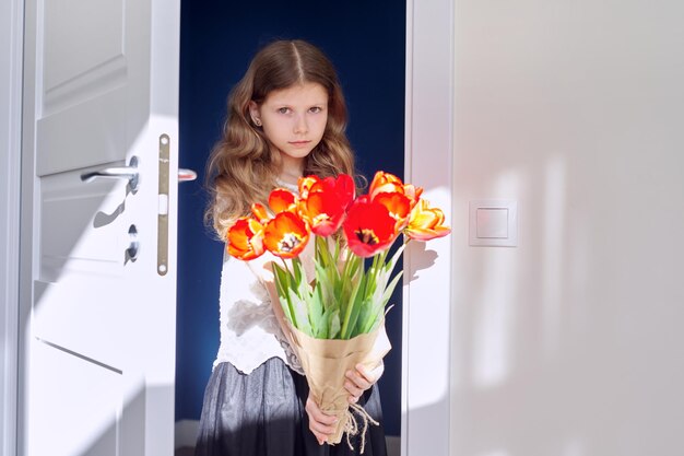 Festa della mamma bambina con bouquet di fiori di tulipani rossi a casa