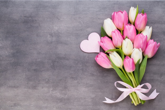 Festa della mamma, festa della donna, Pasqua, tulipani rosa, regali su sfondo grigio.