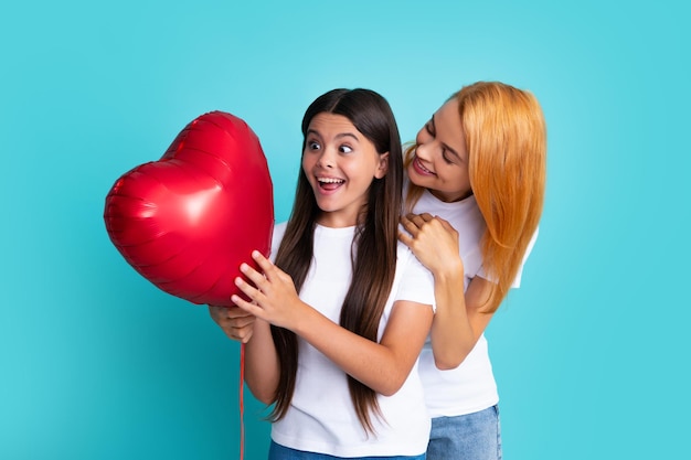 Festa della mamma Madre e figlia sorridenti che tengono il palloncino del cuore d'amore su sfondo blu Mamma