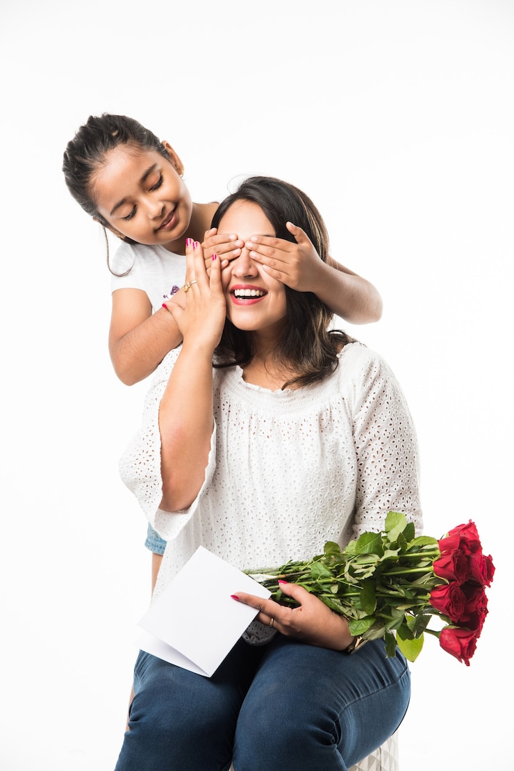 Foto festa della mamma - ragazza indiana e madre che celebrano la festa della mamma con un mazzo di fiori di rose, biglietto di auguri mentre si abbracciano e si baciano