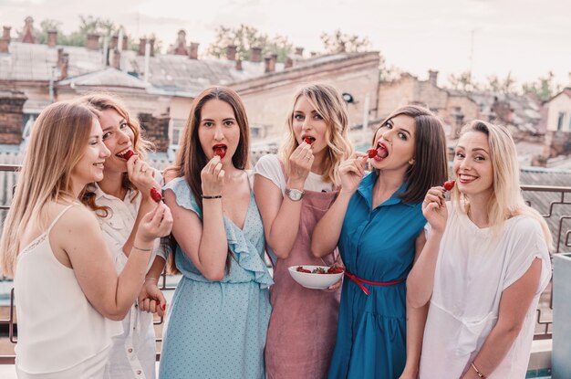 Festa delle ragazze. Belle donne amiche sul balcone divertendosi alla festa di addio al nubilato. Mangiano fragole