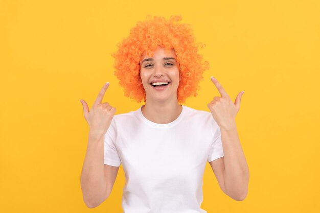 Festa di compleanno delle ragazze felice donna divertente in parrucca riccia esprimono emozioni positive allegra signora indossare parrucca donna ha i capelli arancioni essendo un clown April Fools Day tempo per divertimento