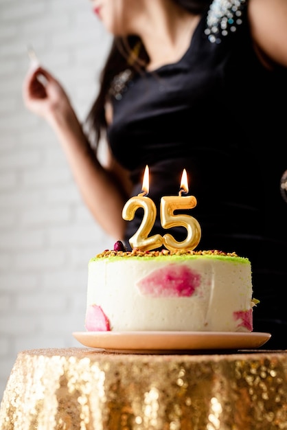 Festa di compleanno donna caucasica in abito da festa nero che accende candele sulla torta di compleanno