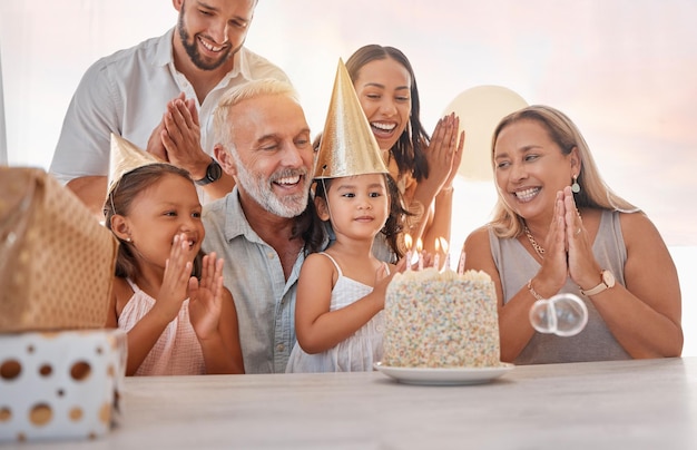 Festa di compleanno in famiglia e torta con festeggiamenti che applaudono e cantano con candela o regalo sul tavolo in casa Genitori e nonni con sorella celebrano l'evento in casa con torta di compleanno