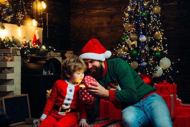 Festa di festa di Natale carino bambino ragazzo e papà vicino all'albero di natale buon natale e...