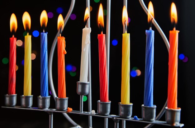 Festa ebraica Hanukkah sfondo Un piatto tradizionale è ciambelle dolci Hanukkah tavola candeliere con candele e trottole su sfondo nero Illuminazione Candele Chanukah Copia spazio