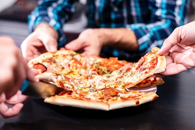 Festa in casa Gli amici mangiano la pizza in piedi sul tavolo