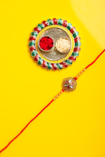 Festa indiana raksha bandhan puja thali e rakhi o braccialetto su sfondo giallo