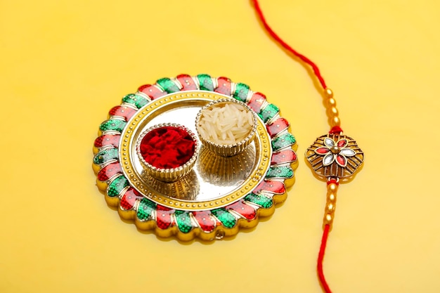 Festa indiana raksha bandhan puja thali e rakhi o braccialetto su sfondo giallo