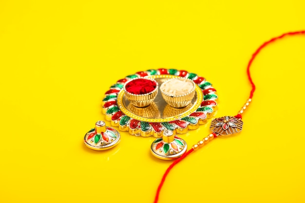 Festa indiana raksha bandhan puja thali e rakhi o braccialetto su sfondo giallo