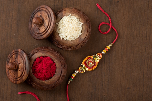 Festa indiana: sottofondo Raksha Bandhan con un elegante Rakhi, Chicchi di Riso e Kumkum