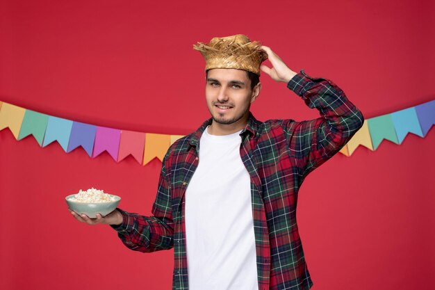 Festa junina felice ragazzo carino che indossa un cappello di paglia che celebra il festival brasiliano toccando il cappello