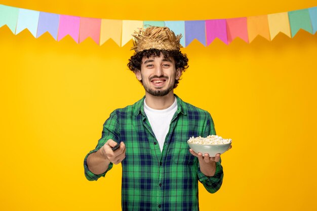 Festa junina giovane ragazzo carino con cappello di paglia e bandiere colorate festival brasiliano con telecomando TV