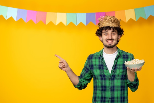 Festa junina giovane ragazzo con cappello di paglia e bandiere colorate festival brasiliano che tiene una ciotola di popcorn