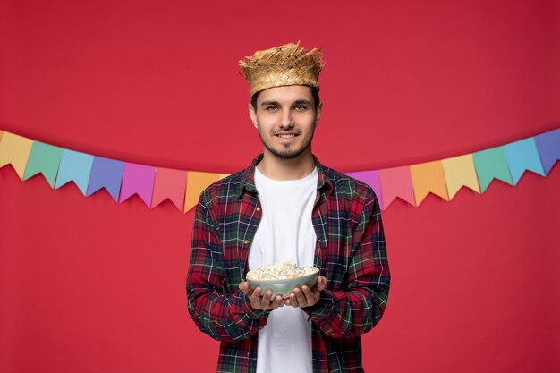 Festa junina simpatico ragazzo felice che indossa un cappello di paglia che celebra il festival brasiliano dando cibo