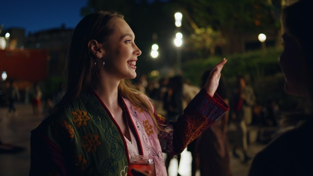 Festa ragazza che tiene il bicchiere bevanda alcolica godendo notte città festa luci di strada