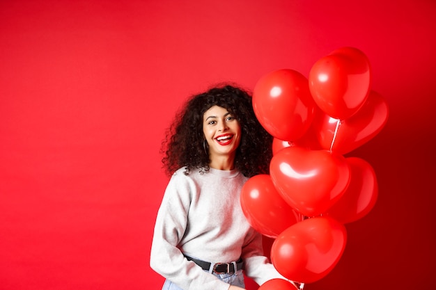 Feste e celebrazioni. Donna felice in posa con palloncini festa su sfondo rosso.