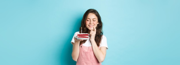 Feste e feste ragazza di compleanno sorridente che celebra guardando sognante la torta con la fabbricazione di candele