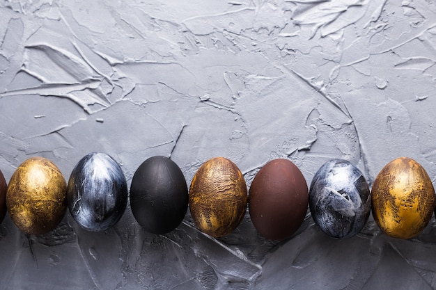 Feste, tradizioni e concetto di Pasqua - uova di Pasqua alla moda scure su fondo grigio con copyspace.