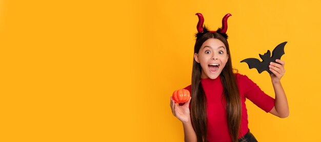 Festeggia la festa autunnale, il divertimento dell'infanzia stupito il bambino malvagio con le corna da diavoletto tiene il pipistrello Halloween kid